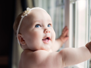 Lexington, KY newborn photographer picture of baby standing against a window on a rainy day