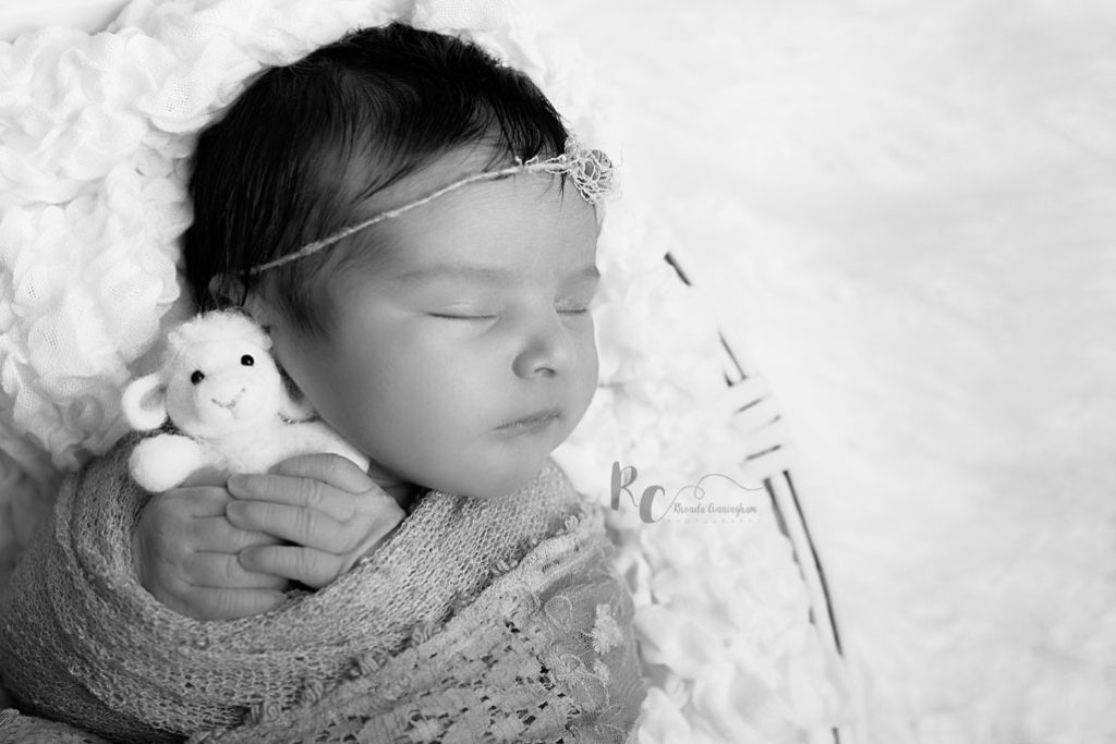 Lexington, KY Newborn Pictures of A black and white photo of a newborn holding a stuffie. Lexington Ky newborn photographer