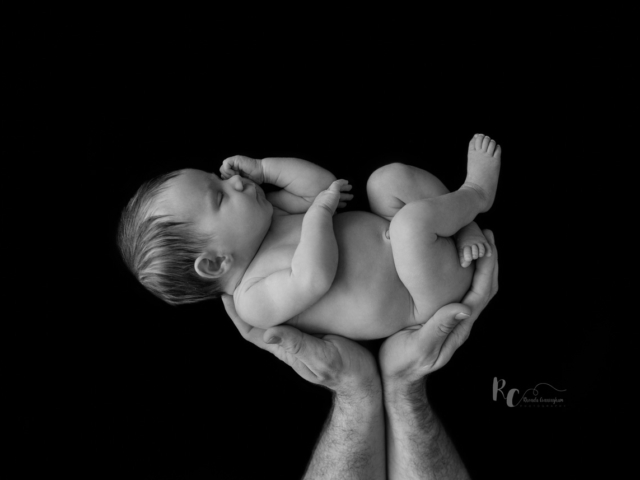 Black and white image of dad's hands holding newborn. Captured by Rhonda Cunningham Photography, Lexington Ky newborn photographer